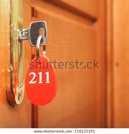 Door handles on wood wing of door and key in keyhole with numbered label