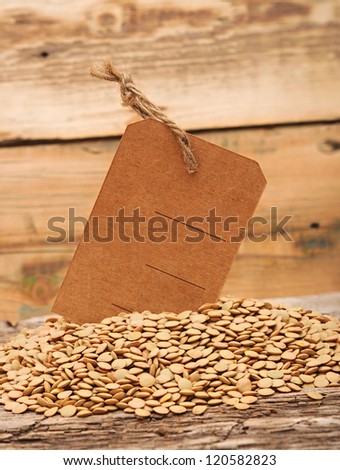 Lentil seeds with blank price tag on a wooden background