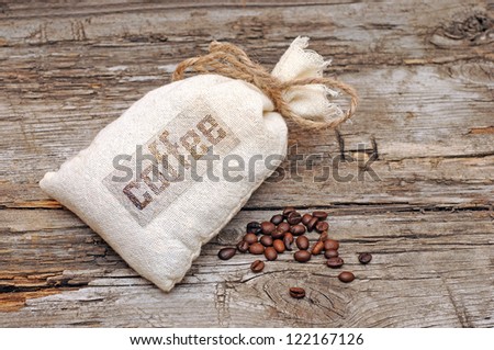 Canvas bag with coffee beans on rustic table with wooden texture