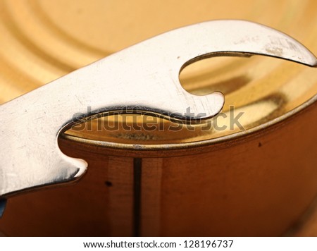 close-up old tin opener opening a can on wooden table
