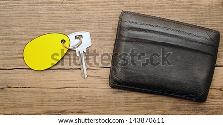wallet and key with blank label on wood background