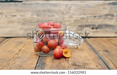 freshly picked plum in glass jar on old wooden table