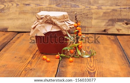 sea buck thorn berries juice on the glass jar on wooden background