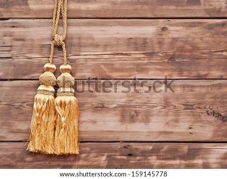 Gold rope with tassel against wooden wall