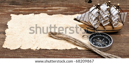 old paper, compass, rope and model classic boat on wood background