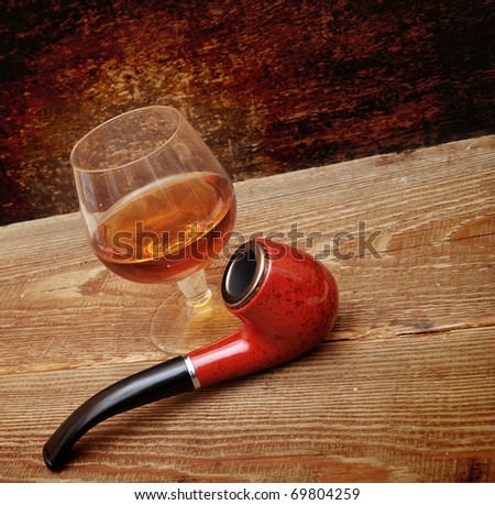pipe and glass of cognac on wood background