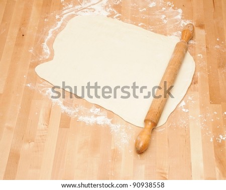 Classic wooden rolling pin with freshly prepared dough and dusting of flour.