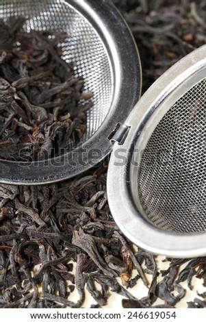 black tea leaves close up with tea strainer