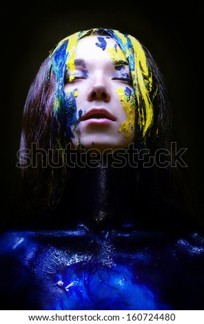 Girl painted blue and yellow on black background
