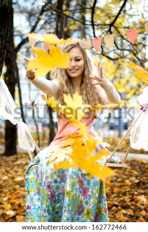 Happy girl throws colorful autumn leaves