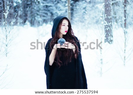 Beautiful witch in black cloak with magi? ball