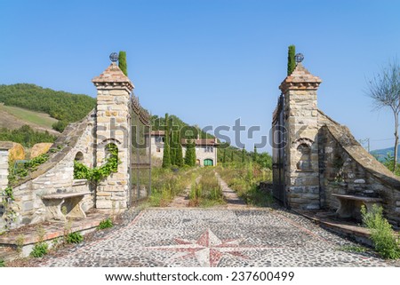 Old abandoned villa in Italy, with iron gate and cypresses, red tile roof, podere on the hill