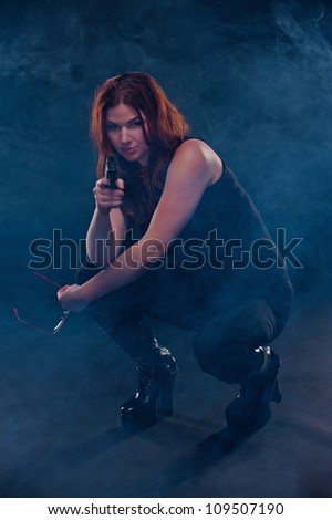 Beautiful woman crouches down prepared to shoot as the fog emerges around her.