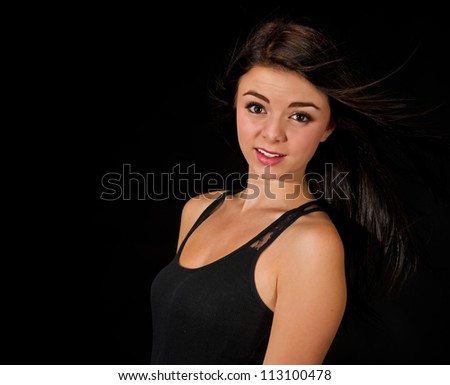 A beautiful teen age girl isolated on a black background look to her left right into the camera with a bit of a smile on her face.