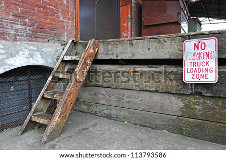 Small ladder for an old wood faced loading dock with a no parking sign.