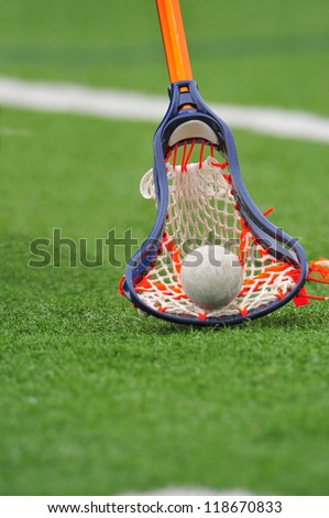 Boys lacrosse stick scoops the ball up off the field for control of the ball and game.