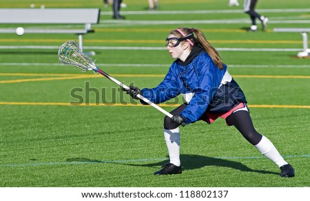 High school girl lacrosse player reaches out to catch the ball.