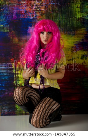 Kneeling punk girl in front of a colorful abstract background.