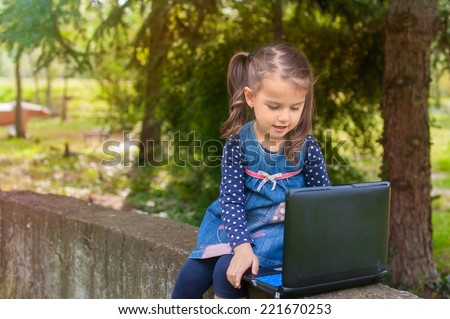 Funny little girl learning with tablet pc in the park, outdoor