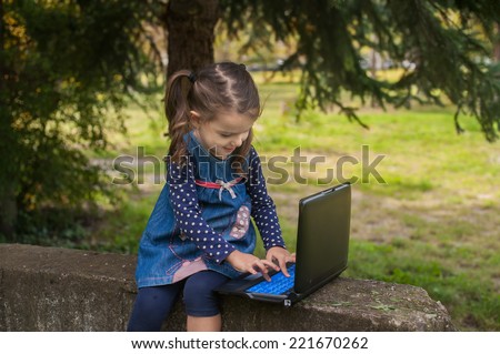 Funny little girl learning with tablet pc in the park, outdoor