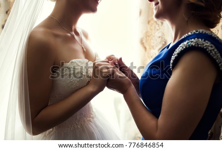 Bride on wedding day holding her mother\'s hands. Concept of relationship between moms and daughters