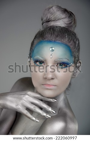 Portrait of a young woman with creative fantasy make up and body painting as Snow Queen or Ice Fairy