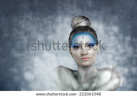 Studio portrait of a young woman with professional make up and body painting as the Snow  Fairy surrounded by snow flakes