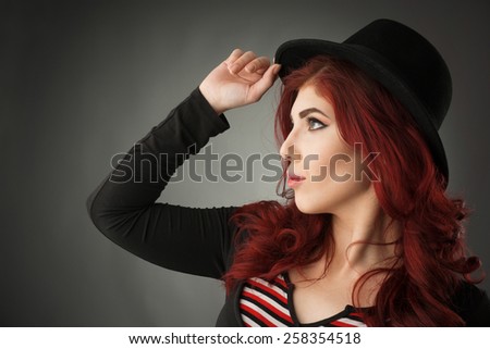 Profile view of a cute redhead posing with a hat