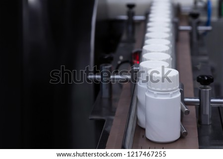 white plastic bottle on the production line of the conveyor at filling machine in the medical factory. selective focus.