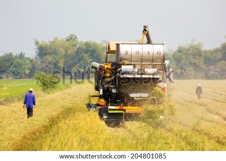 Ayutthaya, Thailand - July 10: Unidentified Thai farmers work with combine harvester in the rice field on July 10, 2014 in Ayutthaya, Thailand.