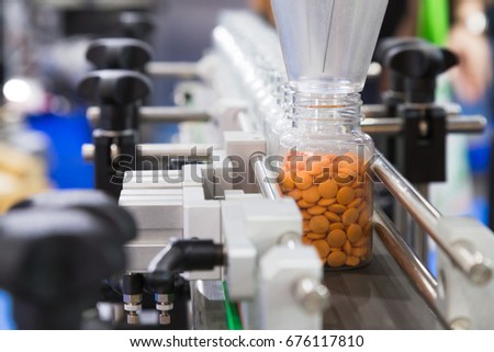 pharmaceutical industry, medicine pills are filling in the plastic bottle on production line machine conveyor at the medical factory. selective focus.