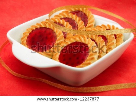 Jelly red biscuits in a white bowl with a vivid red background