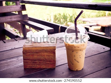 ice coffee and  brown  tissue  paper box on  wooden table