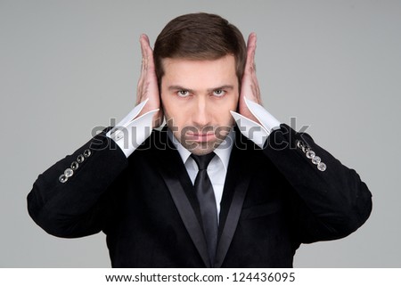 Hear no evil - Business man covering ears. Over grey background