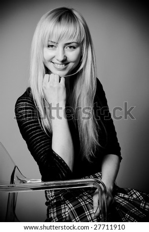 Black and white studio portrait of young woman siting on chair
