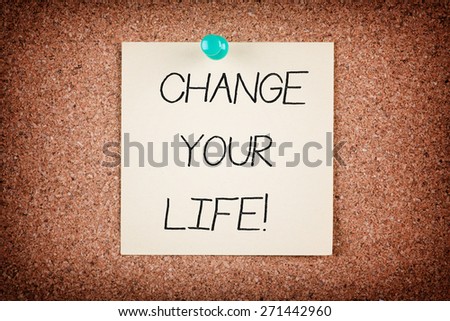 Yellow reminder sticky note on cork board with CHANGE YOUR LIFE text