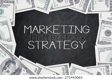 MARKETING STRATEGY text on a blackboard with border made of 100 US dollars.