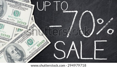 UP TO -70% SALE text written on a blackboard with frame made of 100 US dollars.
