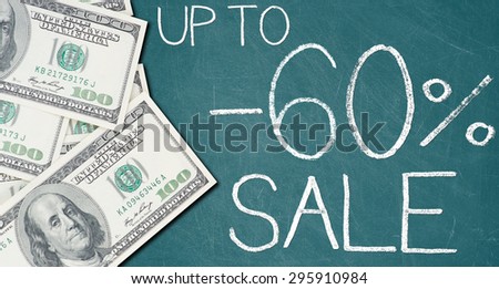 UP TO -60% SALE text written on a green chalkboard with frame made of 100 US dollars.