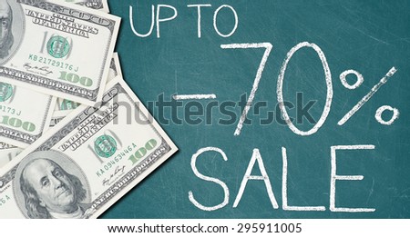 UP TO -70% SALE text written on a green chalkboard with frame made of 100 US dollars.