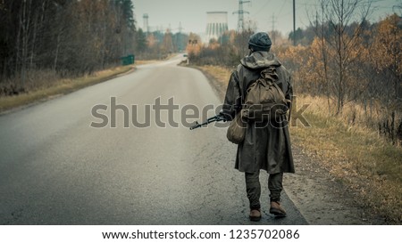 Survivor soldier in gas mask and with russian assault rifle walking in the danger radioactive zone of wastelands. Post apocalypse. Nuclear war.