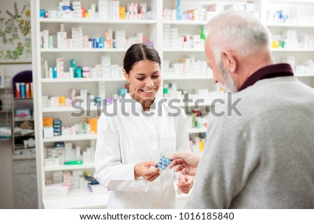medicine, pharmaceutics, health care and people concept - happy pharmacist giving medications to senior man customer