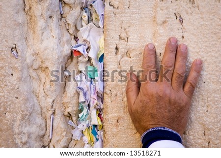 Hand of praying men on the Western Wall filled by wishes in Jerusalem.