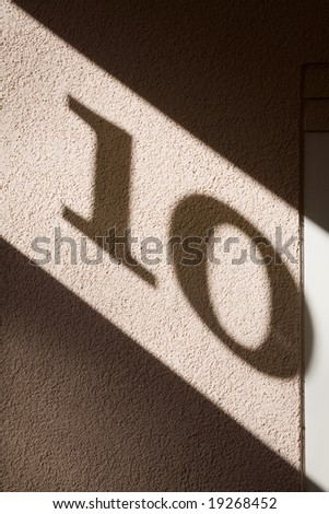 Number ten. Shadow light print on the house wall.