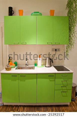 Green kitchen with orange and black supplements in retro style.