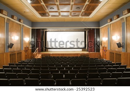 Empty old retro style cinema auditorium with line of chairs and stage with silver screen. Ready for adding your own picture.