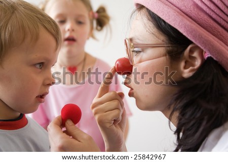 Clown-doctor : boy is watching clown how to put red nose on.