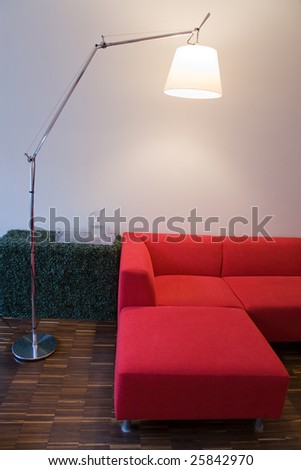 Living room interior with wooden floor, red sofa and lighting lamp.