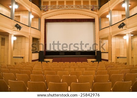 Empty old theater auditorium with arc line of chairs and stage with silver screen. Ready for adding your own picture.
