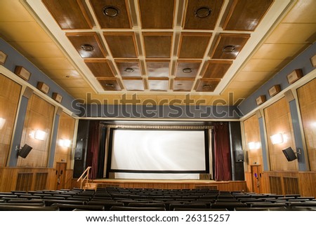 Empty old retro style cinema auditorium with line of chairs and stage with silver screen. Ready for adding your own picture.